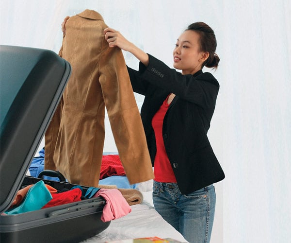 Woman packing clothes into a suitcase