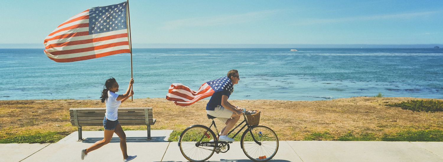 Couple running and cycling down a path holding an American flag