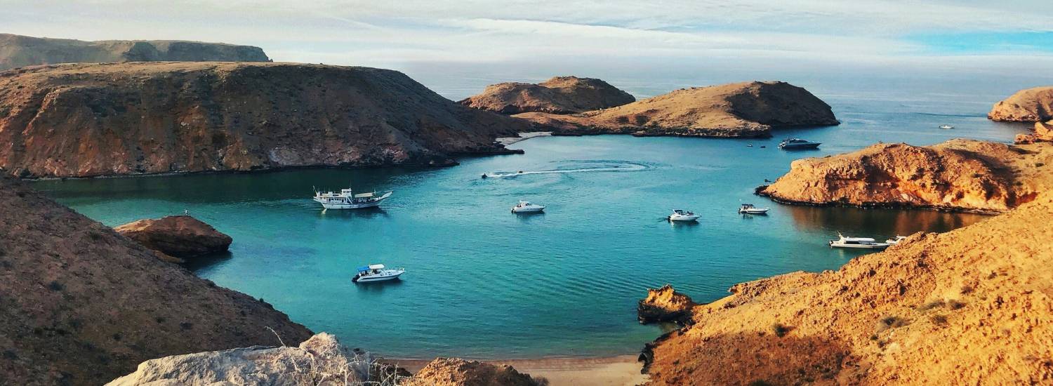 Boats in a bay surrounded by rocky mountains in Oman