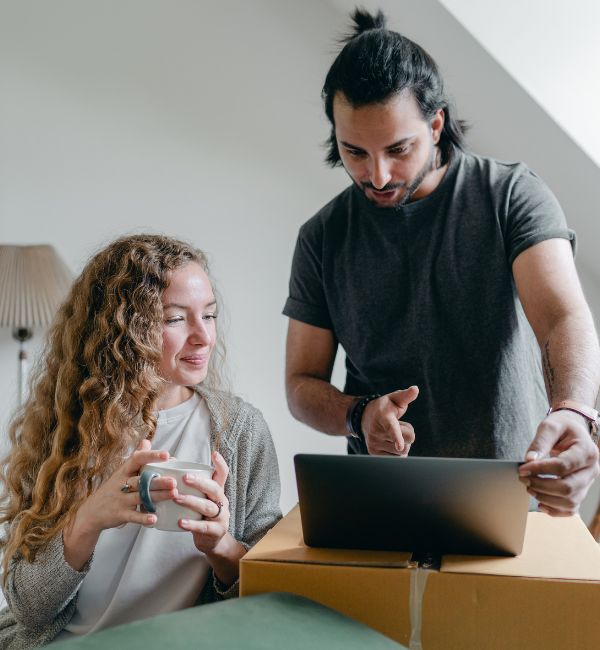 Couple using a laptop beside packed moving boxes