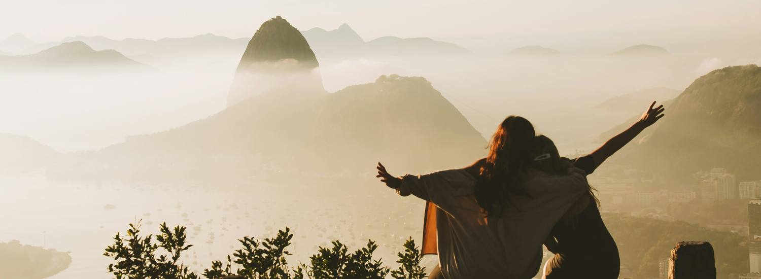 Two friends looking out across mountains and ocean in Brazil