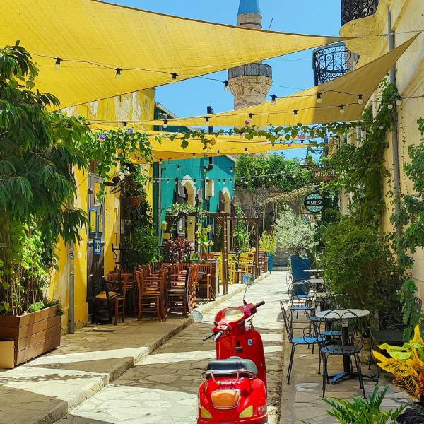 Red motor scooter parked near yellow and blue building during daytime in Cyprus