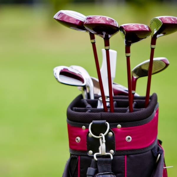 Close up of golf clubs in a bag in a blurred green golf course