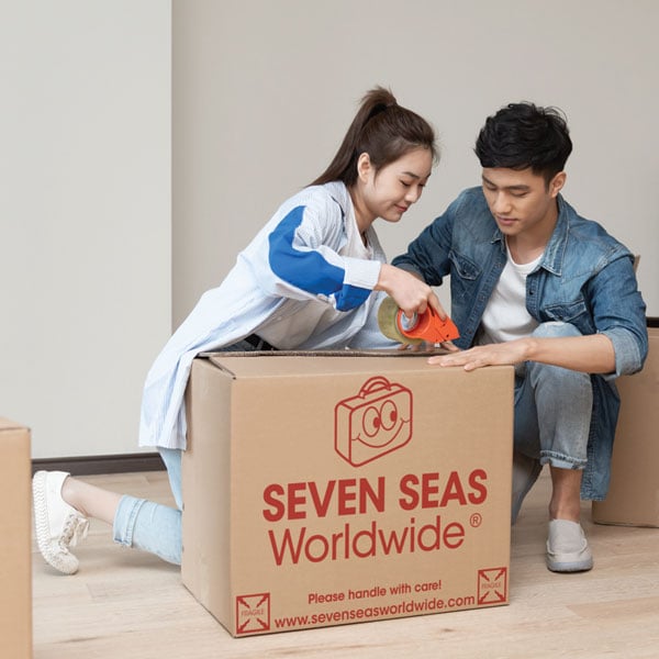 Two international student packing a shipping box