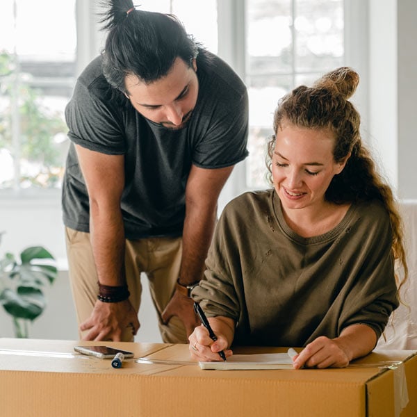 Couple writing a list on a packing box