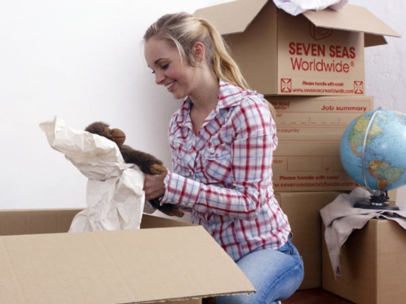 Young lady packing teddy into cardboard box