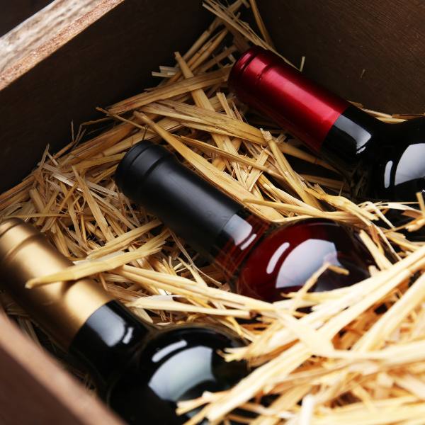 Close-up of three wine bottles in a wooden crate