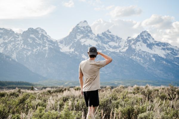 Man standing in a field looking at mountains