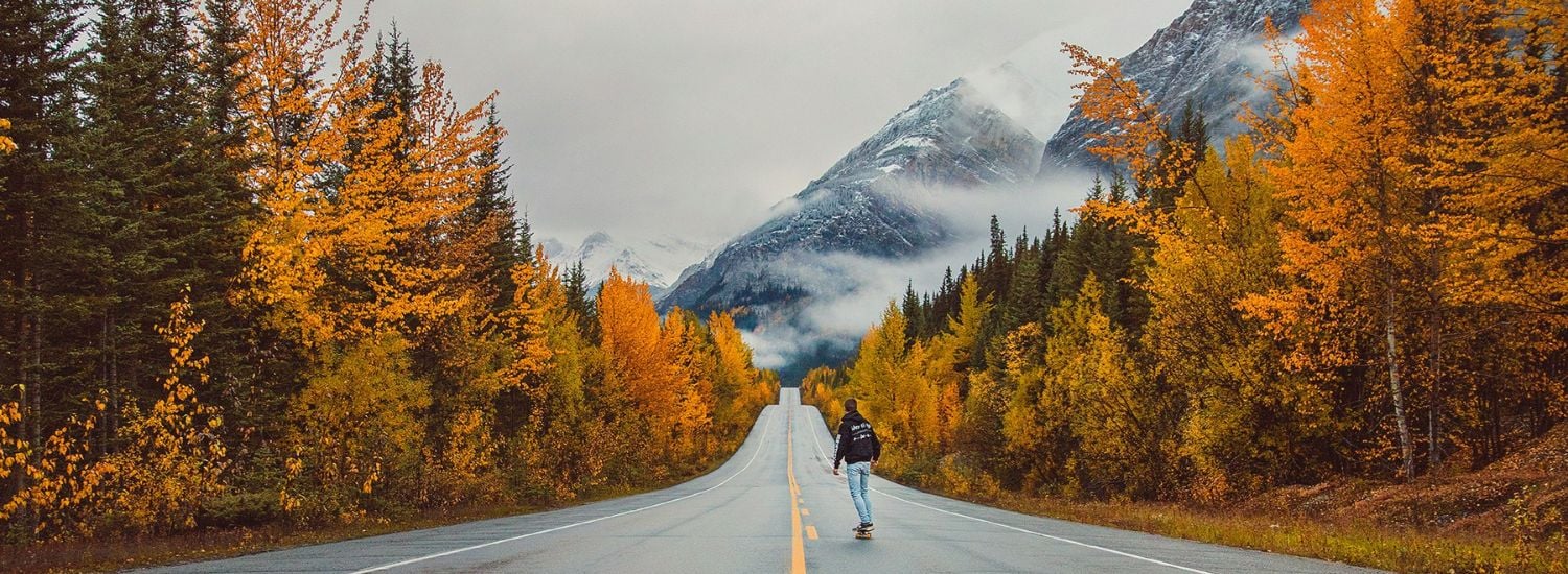 Man skateboarding along a road in Canada