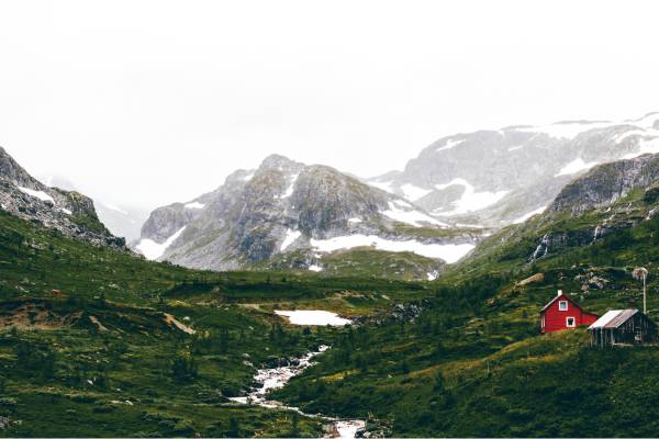 Small red house with mountains in the background in Norway
