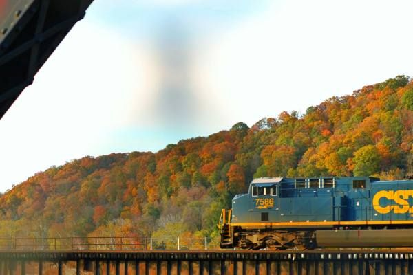 A blue train travels through autumn hills in West Virginia