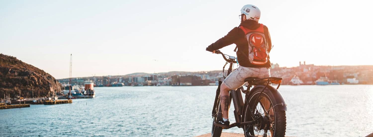 Man on an electric bike wearing a helmet a road overlooking the sea