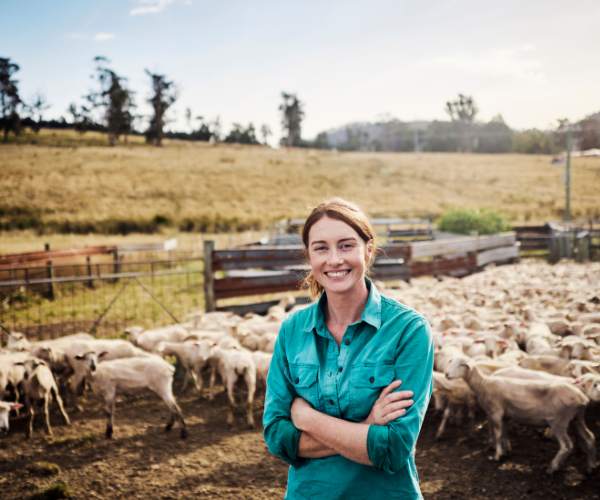 Smiling young woman in a goat pen on a farm in Australia