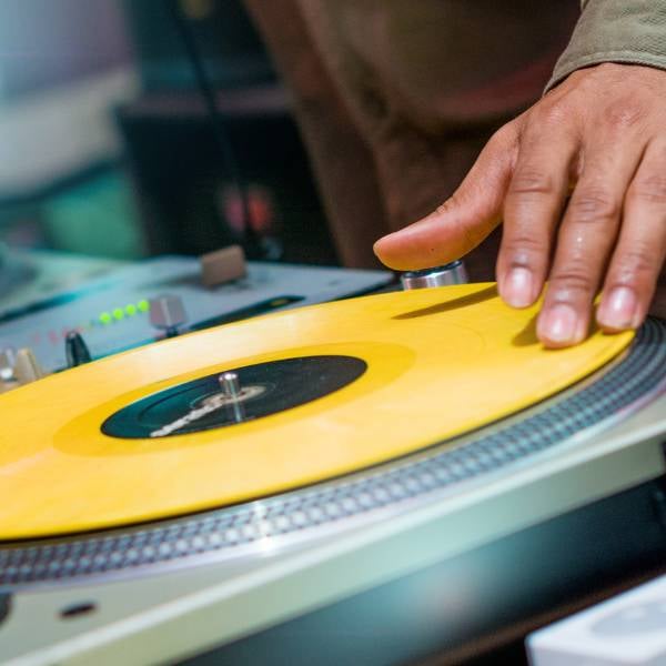 DJ scratching a yellow vinyl record on a turntable
