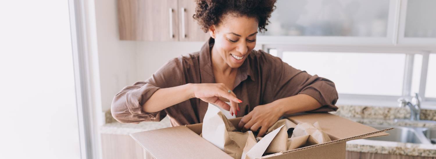Woman packing items into a cardboard box in a kitchen