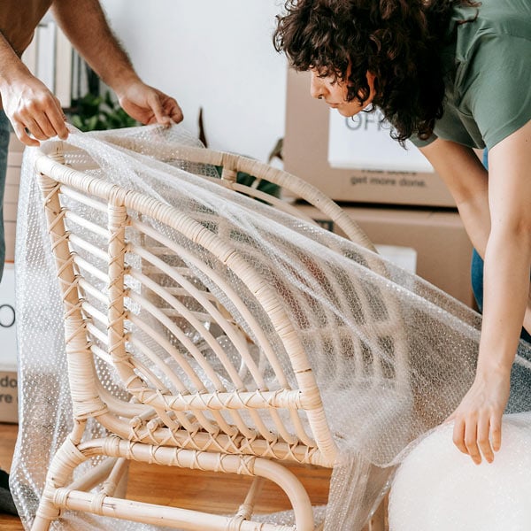Couple wrapping a chair in plastic