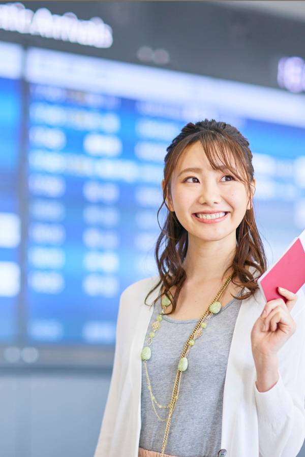 Smiling woman holding a red passport in an airport