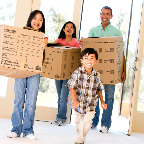 Family carrying cardboard boxes into a house