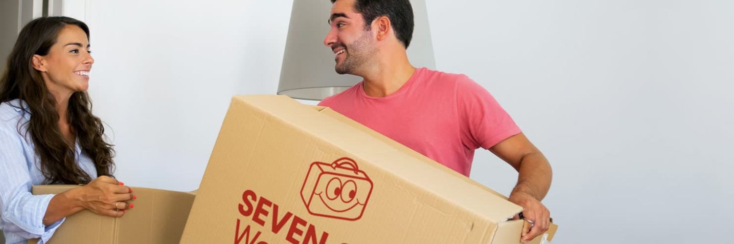 Couple carrying a packed moving box while preparing for an international move