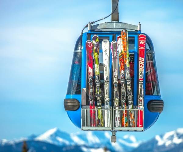 A row of skis in the back of a cable car against mountains