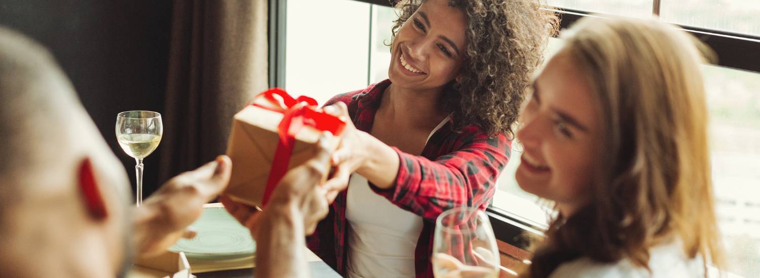 Woman handing a gift to a friend at a table