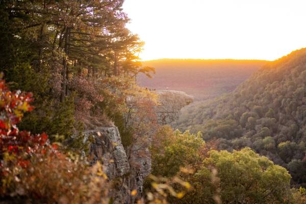 The sun is setting over the mountains and trees in Arkansas