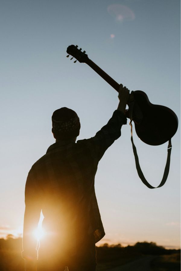A man holding a guitar up in the air