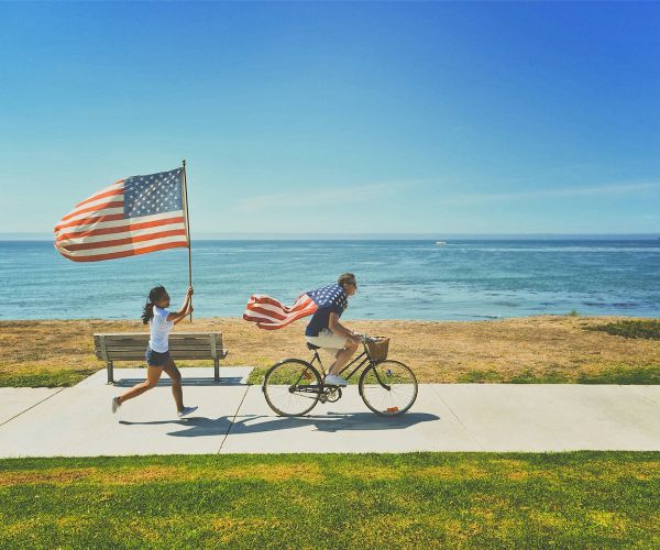 Couple waving American flags and running along a beach