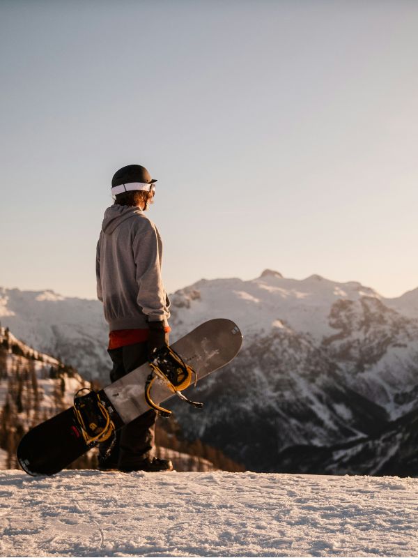 Person holding a snowboard looking out over mountains